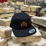 A black 5-panel cap with a yellow embroidered 'EOS 1600' logo on the front, resting on stacked stone bricks.
